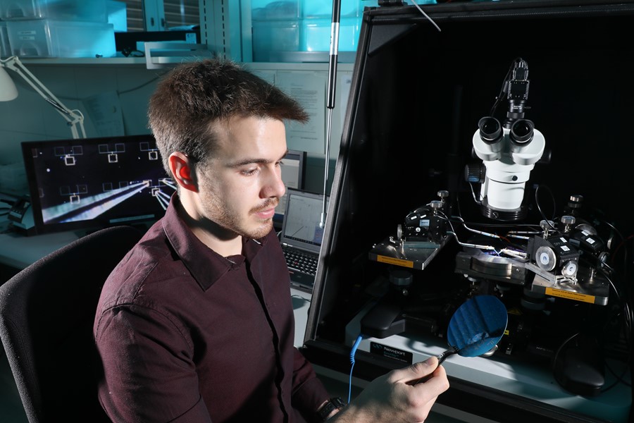 Guillherme Migliato Marega, the lead author on the two papers, inspecting a wafer with MoS2 circuits (Credit: Allain Herzog, EPFL)