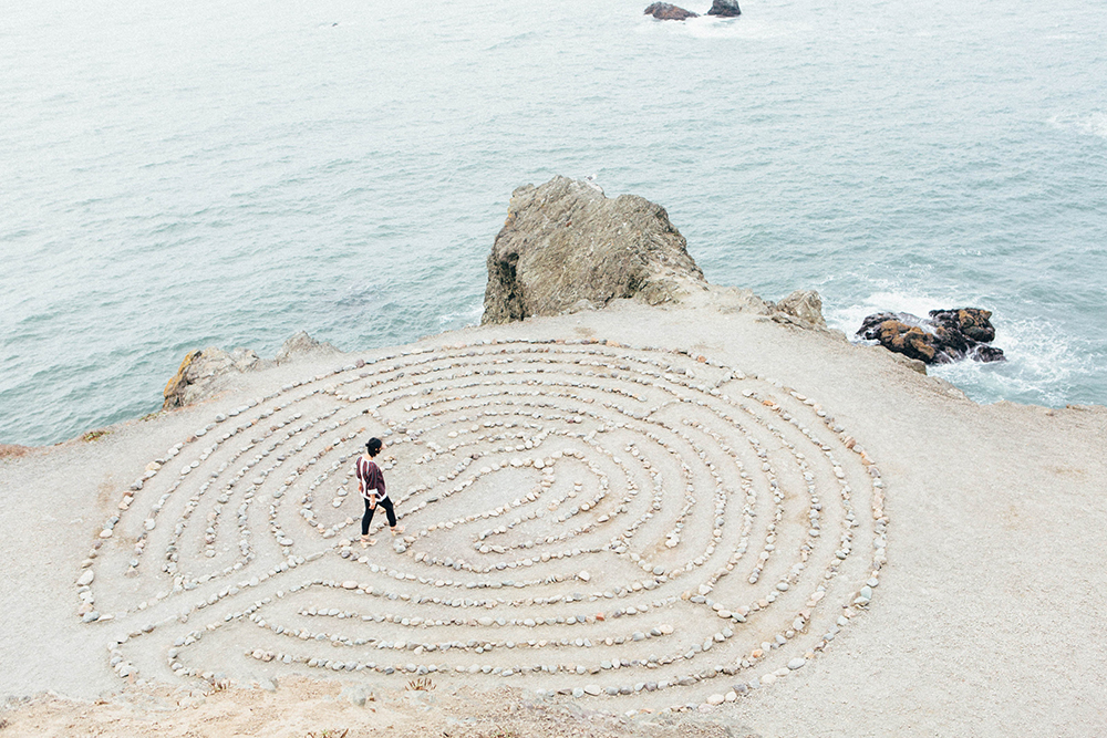 a maze on the sand and a person near the sea to represent "Diversity in Graphene" 2023