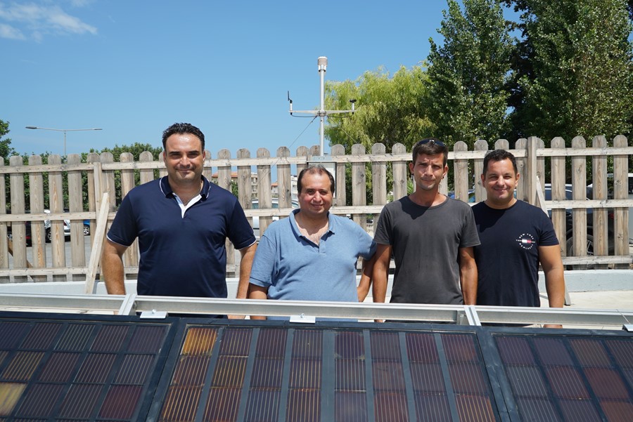 four men standing in front of a solar panel
